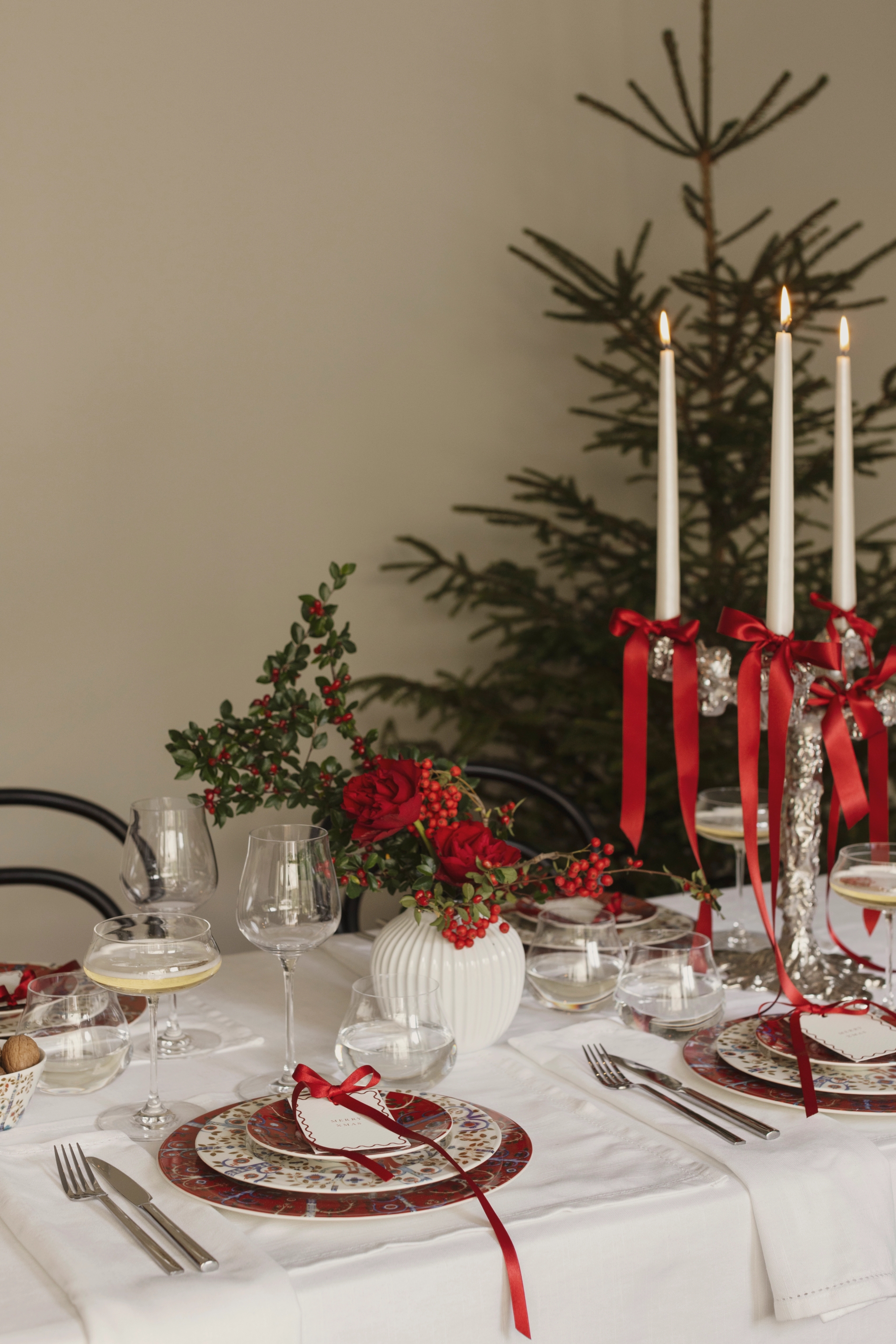 a table set for a christmas dinner with a christmas tree in the background