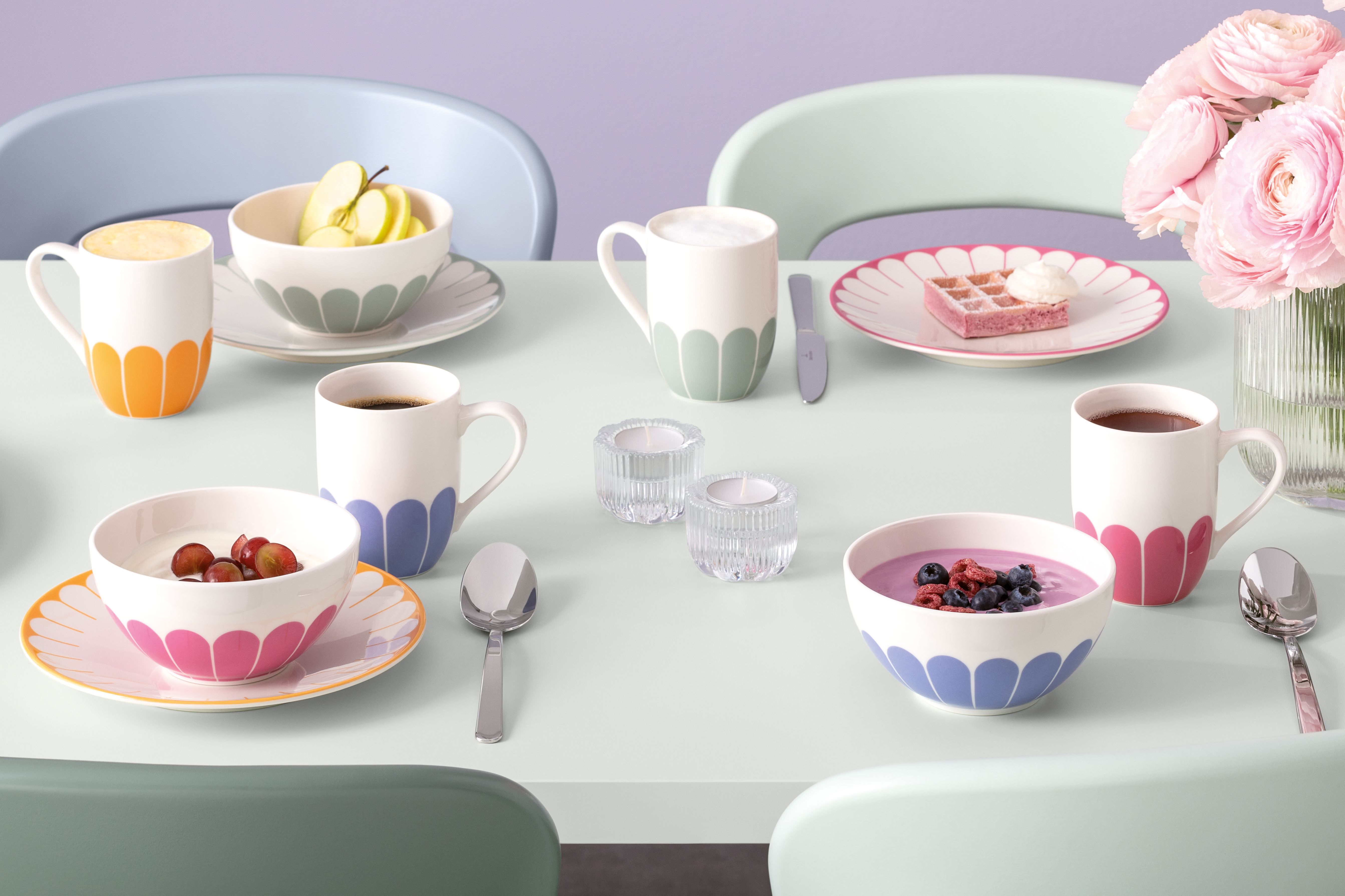 Fargerik frokostborddekking med mønstrede kopper og skåler fylt med kaffe, frukt og yoghurt.