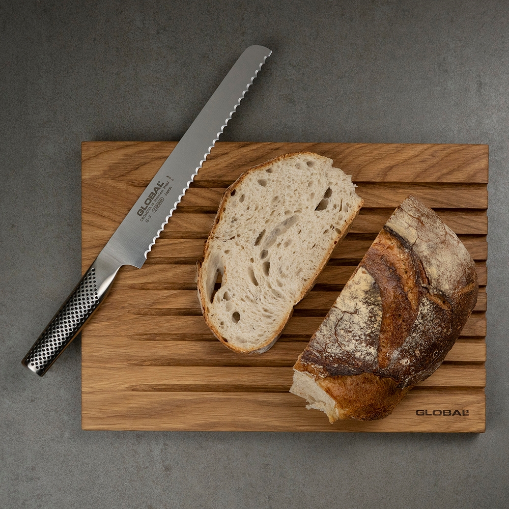 Brødkniv og lyst brød på et skjærebrett i tre