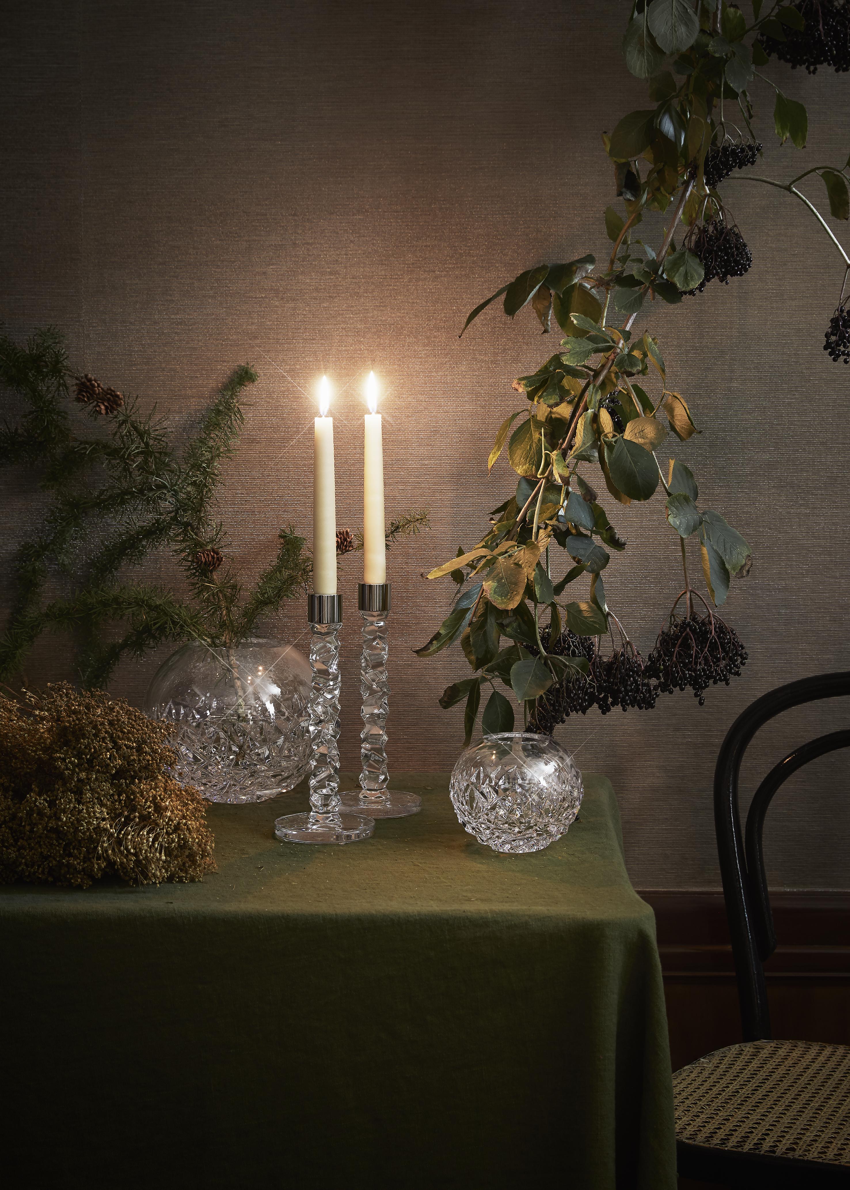 et bord med to lys og en vase på.