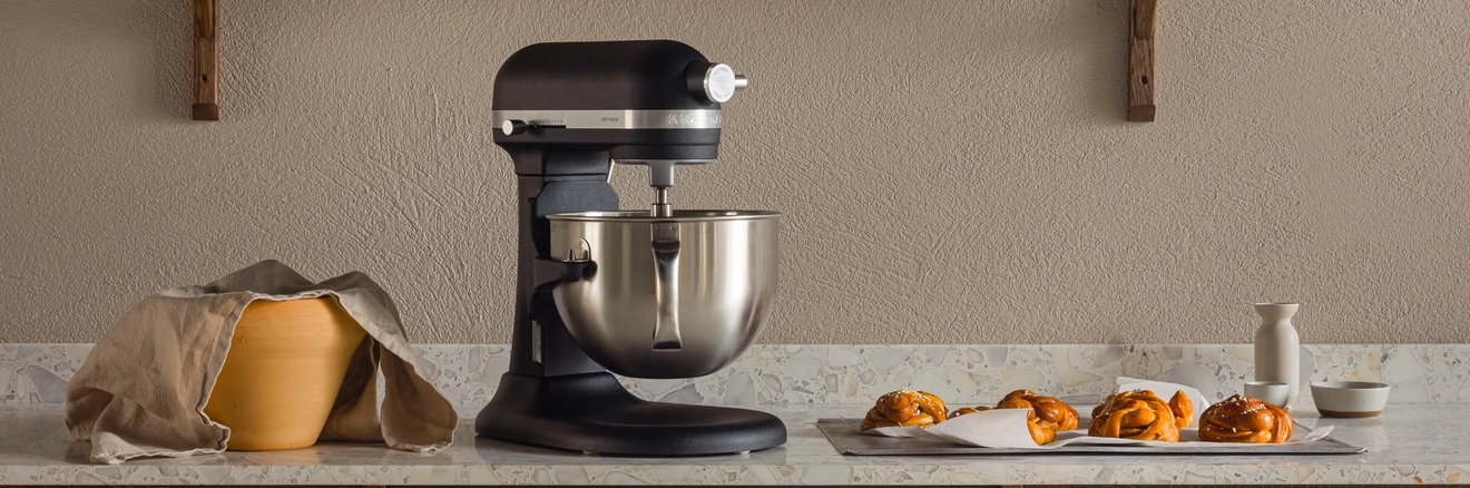 Svart kjøkkenmaskin på en kjøkkenbenk med baketilbehør