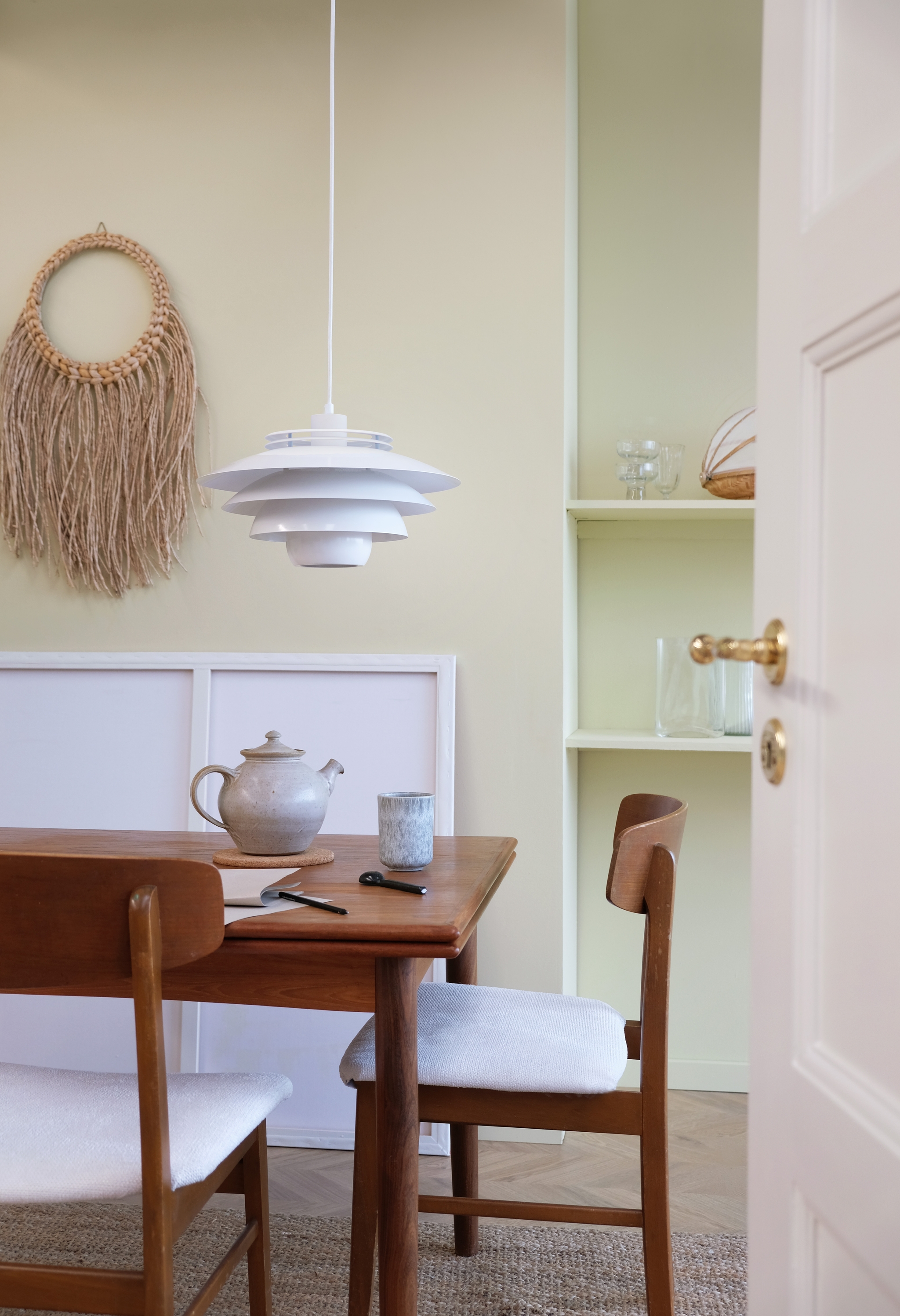 matplats med ett brunt träbord och stolar omgiven av rosa vägg med en vit taklampa ovanför