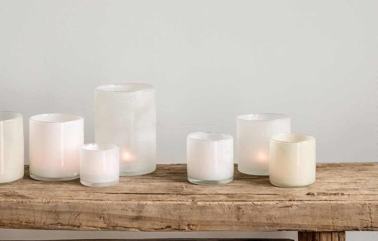 Vita ljuslyktor i olika storlekar på en träbänk