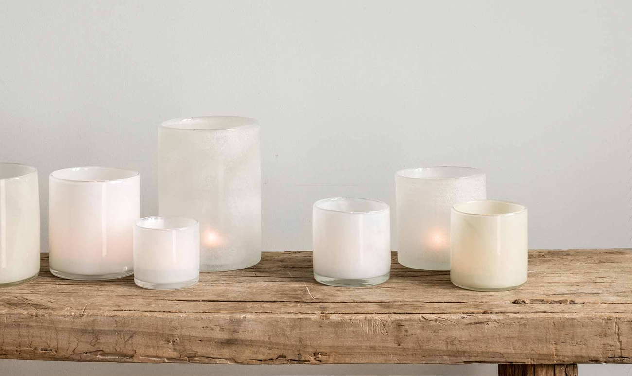 Vita ljuslyktor i olika storlekar på en träbänk