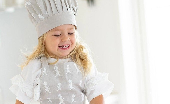 Barn i barnförkläde och kockmössa från solstickan i grått