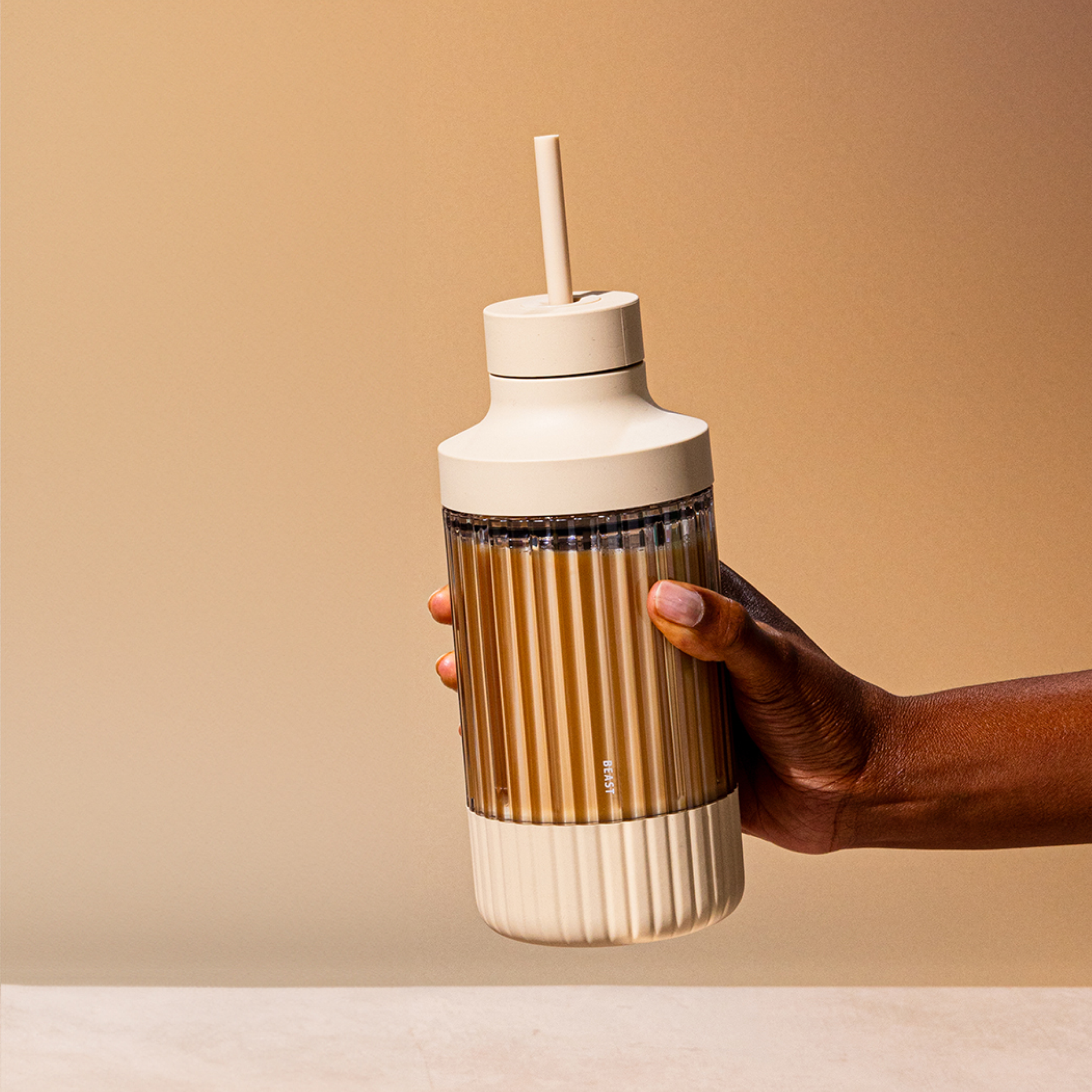 En person håller en to go mugg med smoothie och ett sugrör i