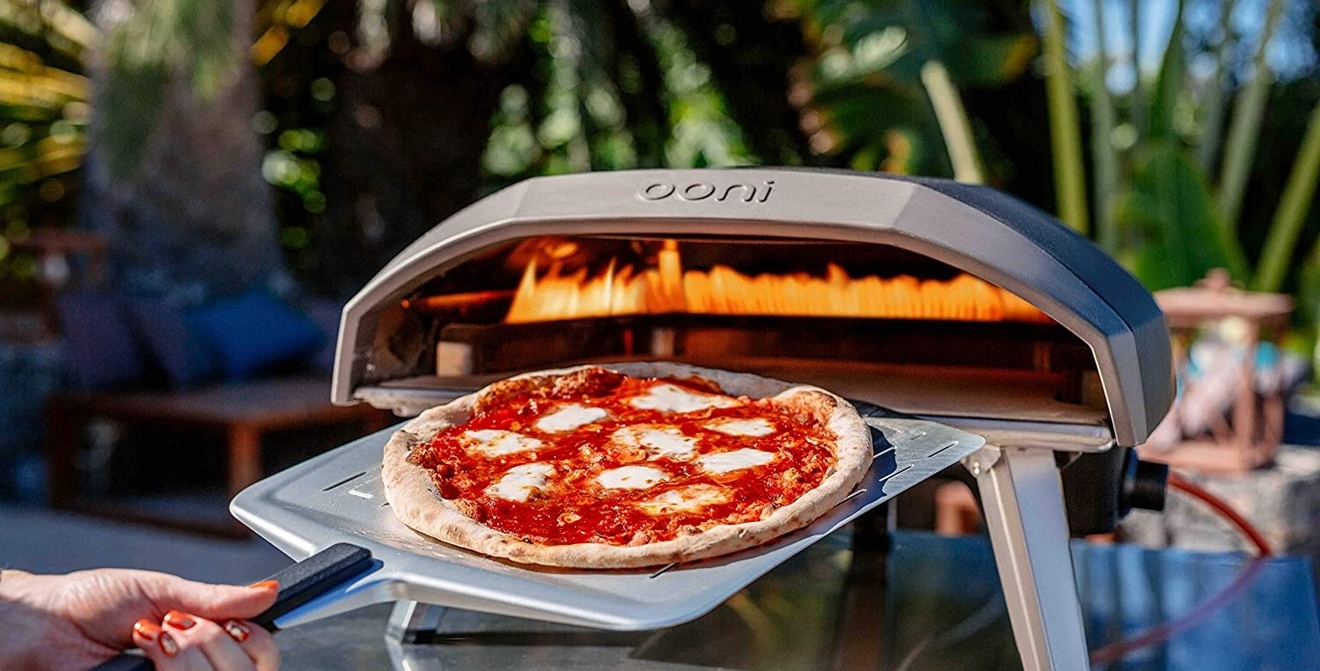 Pizzaugn gasol från Ooni med en pizzaspade med en nygräddad pizza på