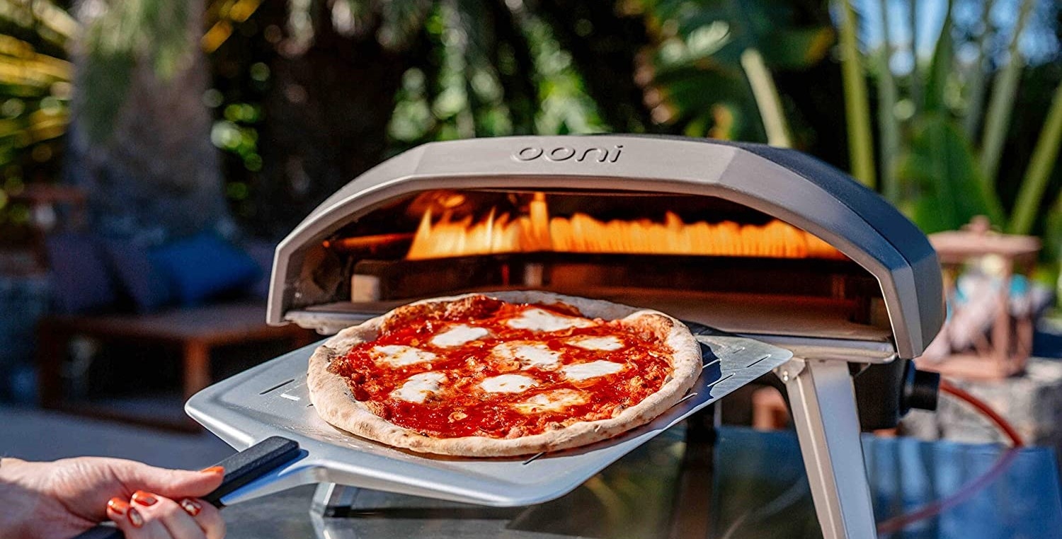 Pizzaugn gasol från Ooni med en pizzaspade med en nygräddad pizza på