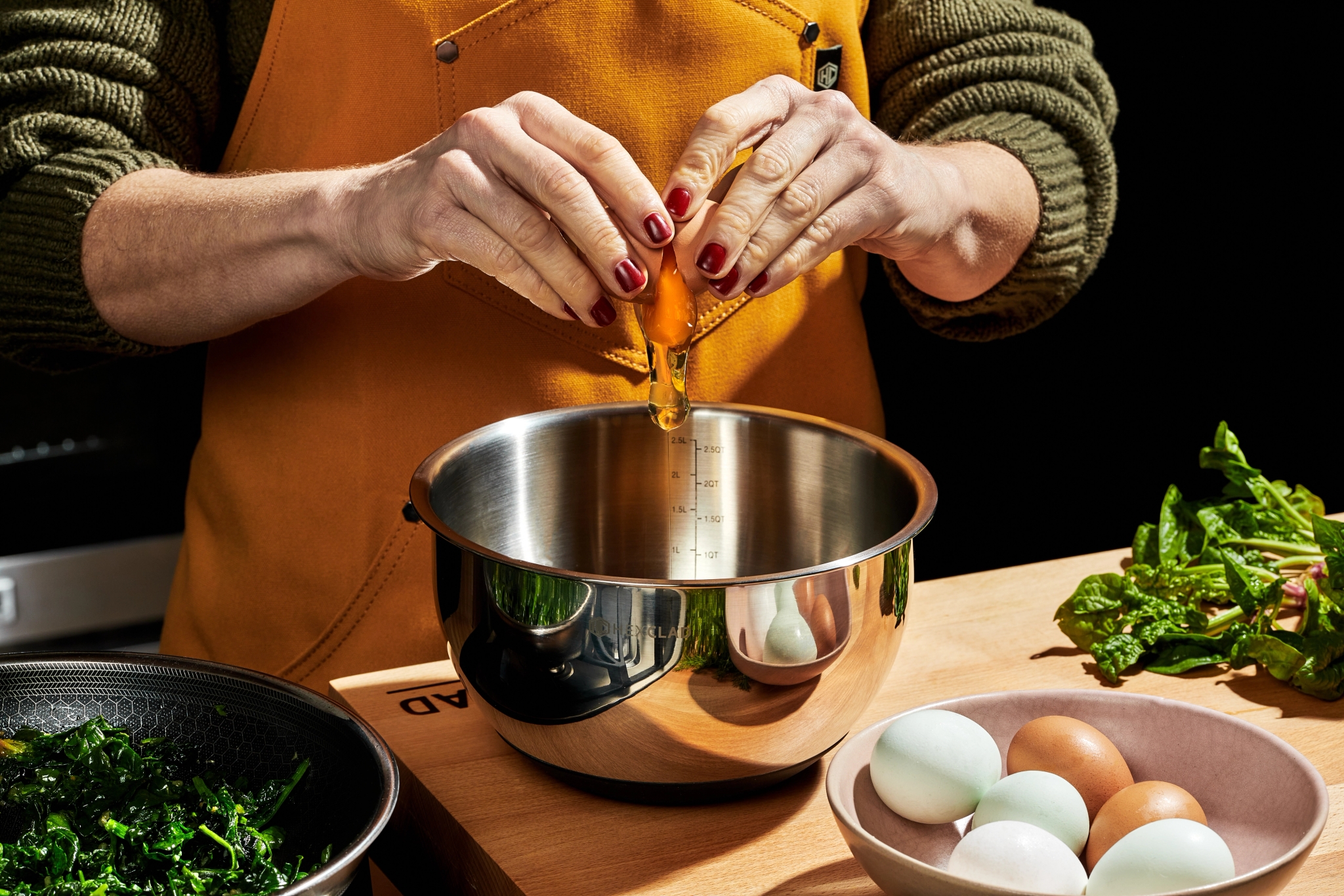 henkilö rikkoo kananmunaa metallikulhoon.