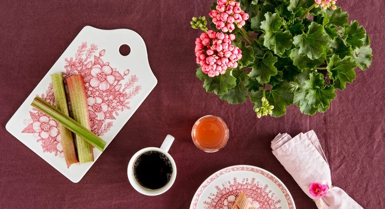 Brickor & Underlägg, Huvila serveringsbricka med rabarber på uppdukat på bord med kaffe och kaka och blomma med gröna blad och rosa blommor