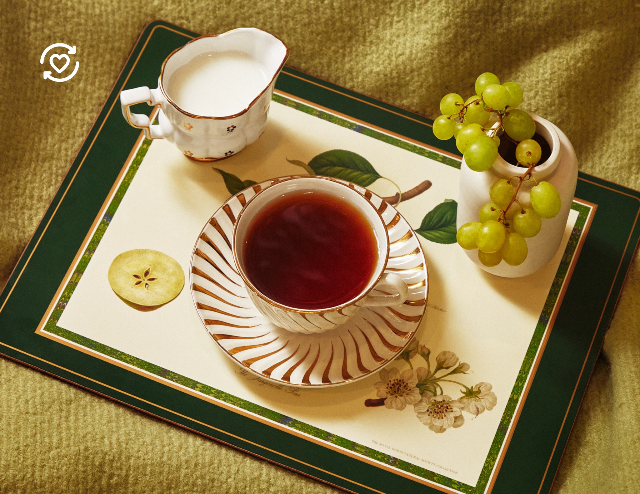 En tekopp och en liten mjölkkanna på en blommig bricka