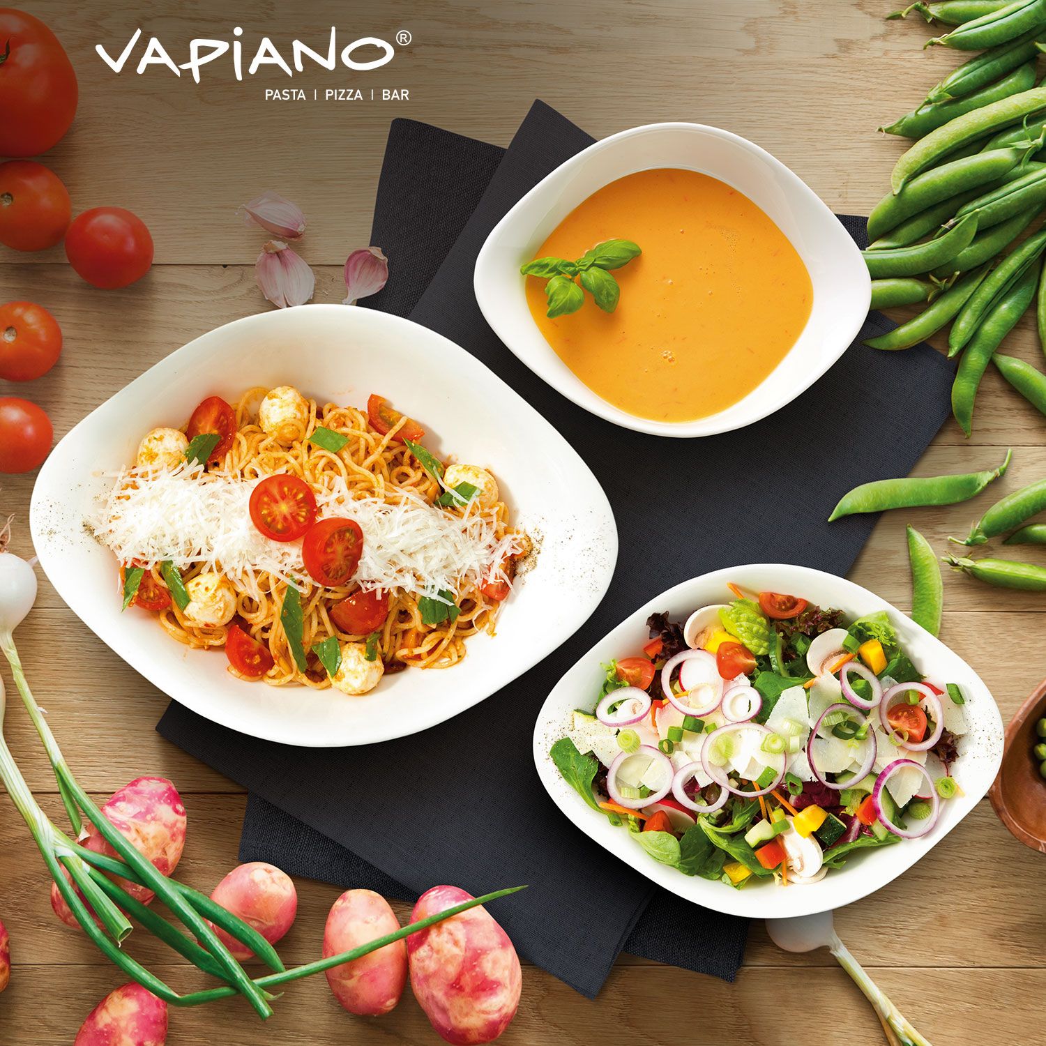 Vapiano presenterar en färgstark italiensk måltid med pasta, sallad och soppa omgiven av färska grönsaker.