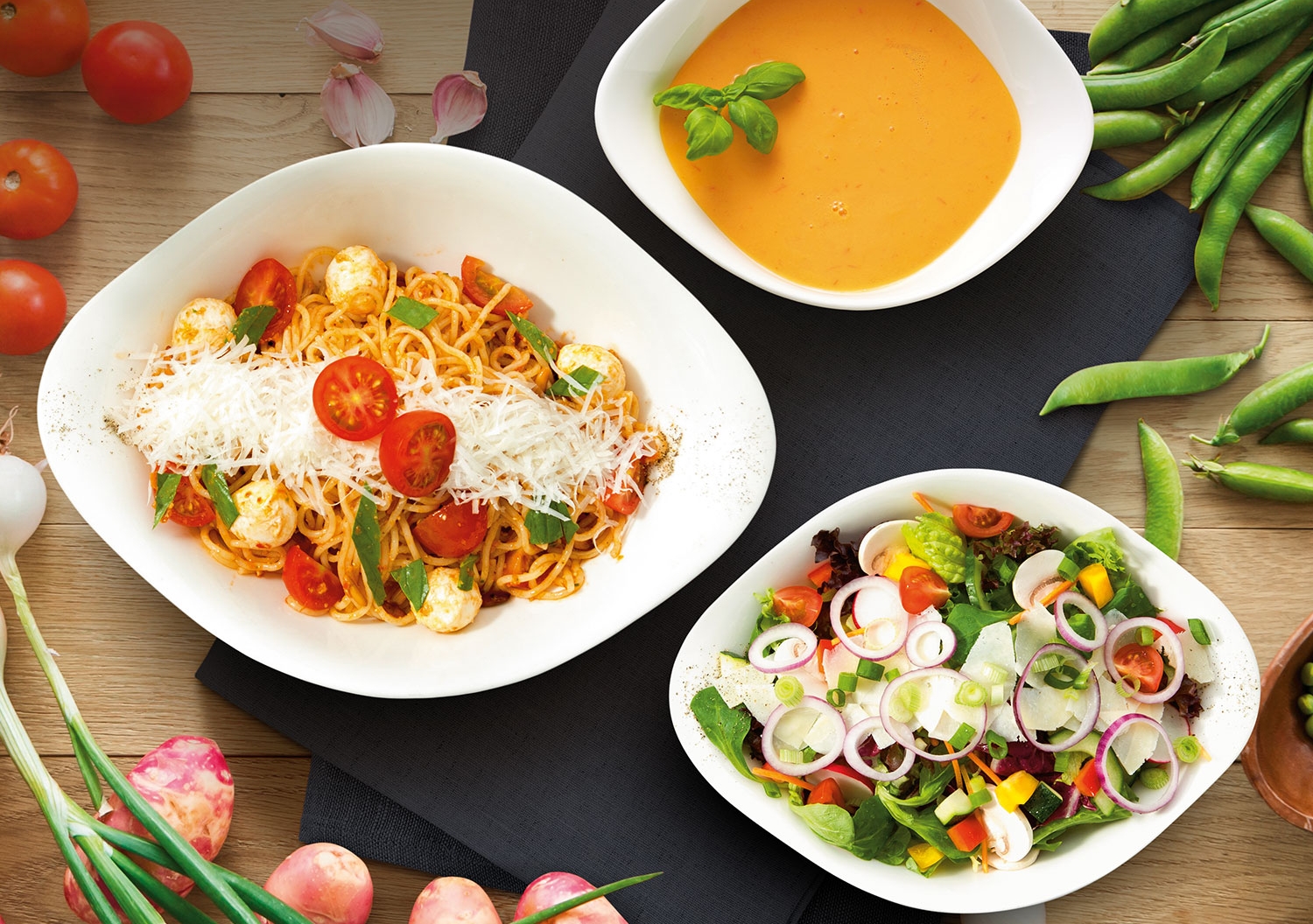 Vapiano presenterer et fargerikt italiensk måltid med pasta, salat og suppe, omgitt av friske grønnsaker.