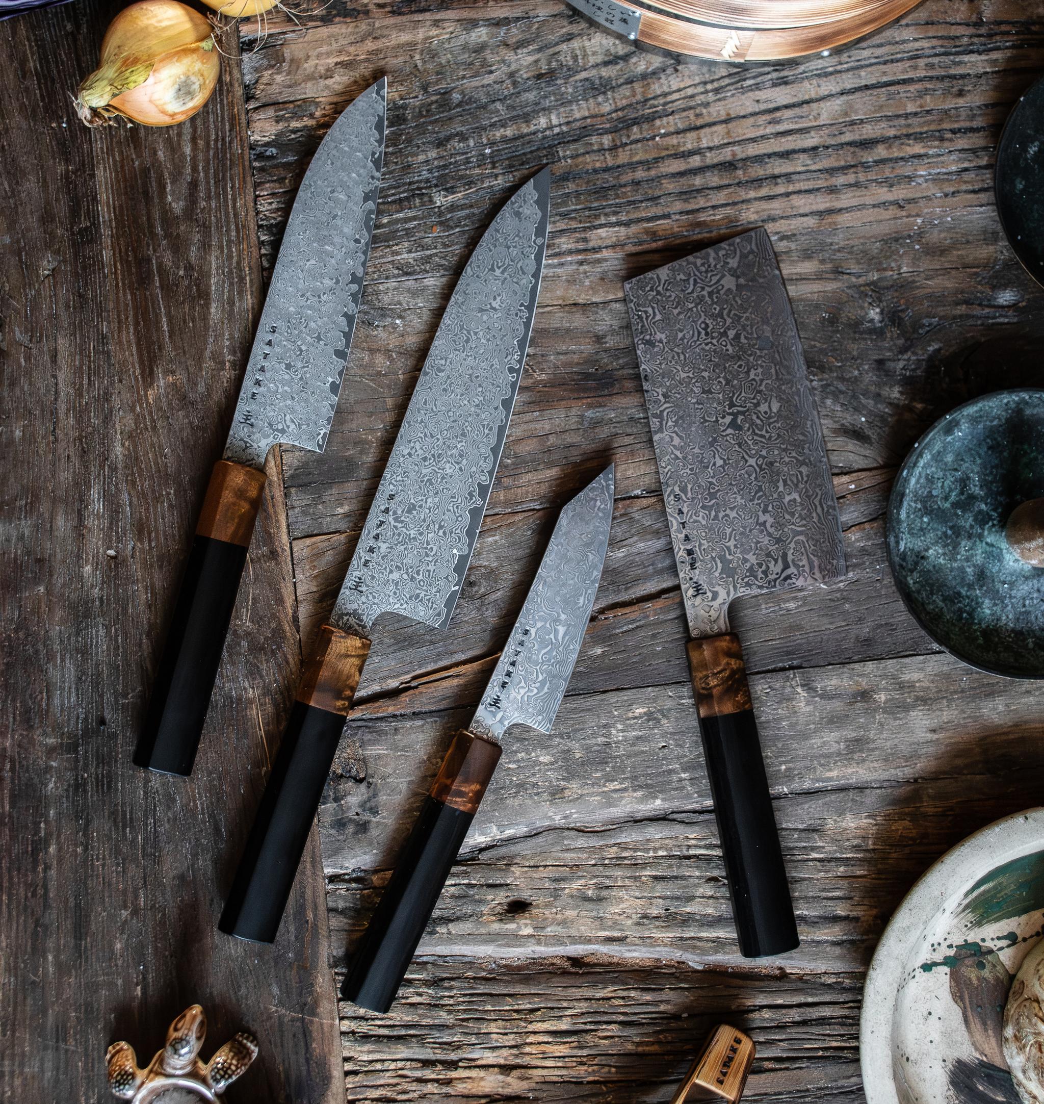Ett set med fyra damaskusstålknivar med svarta och trähandtag på en rustik träyta