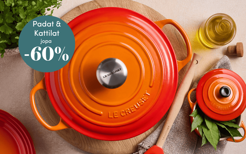 Oranssi Le Creuset valurautapata ja nuolija puisella alustalla pöydällä