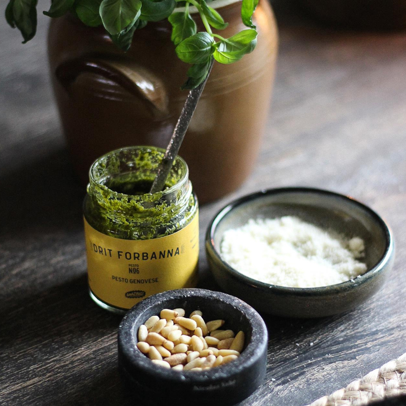 Såser pesto med salt och pinjenötter och en kruka basilika