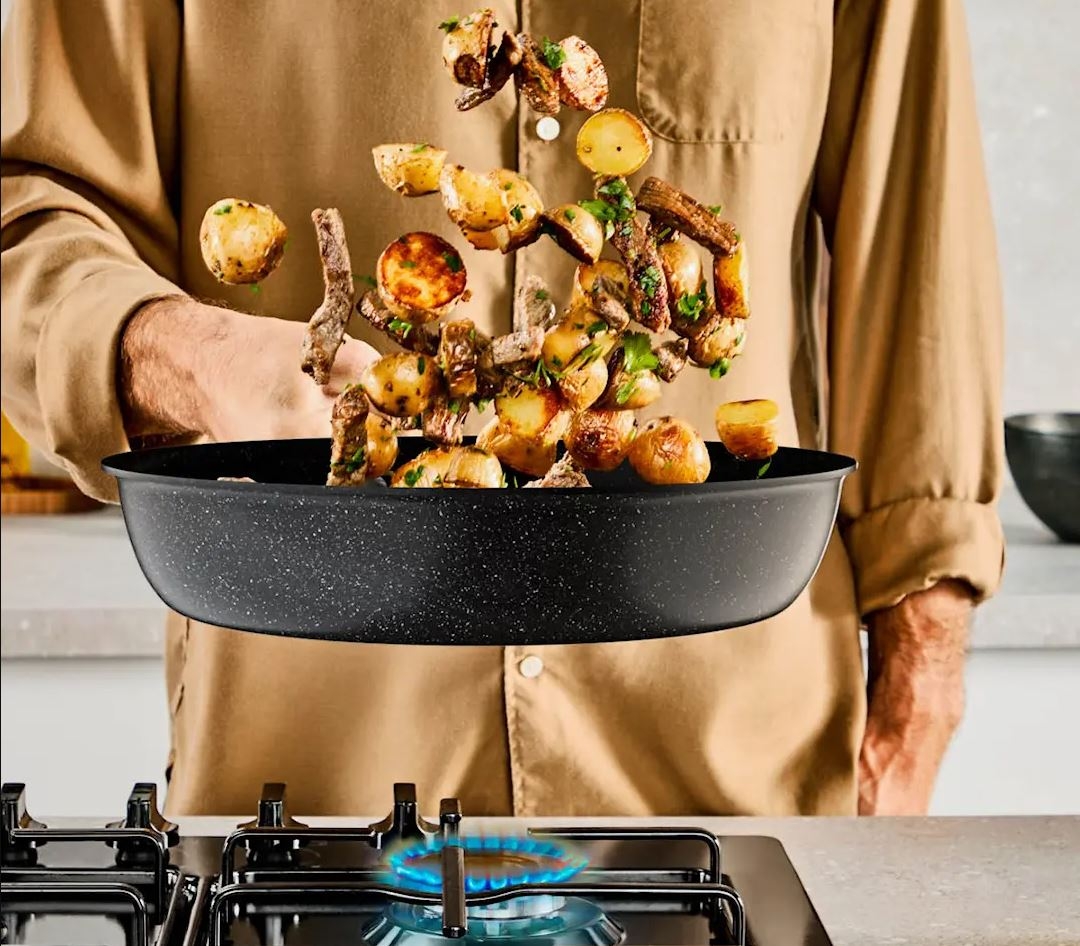 a man is cooking potatoes in a frying pan on a stove .
