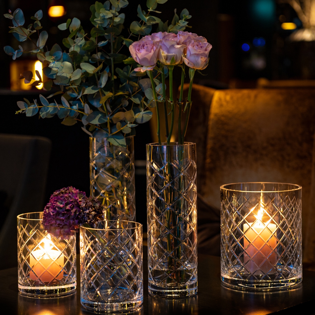 Höga krisallvas med rosa rosor och runt omkring levande ljus