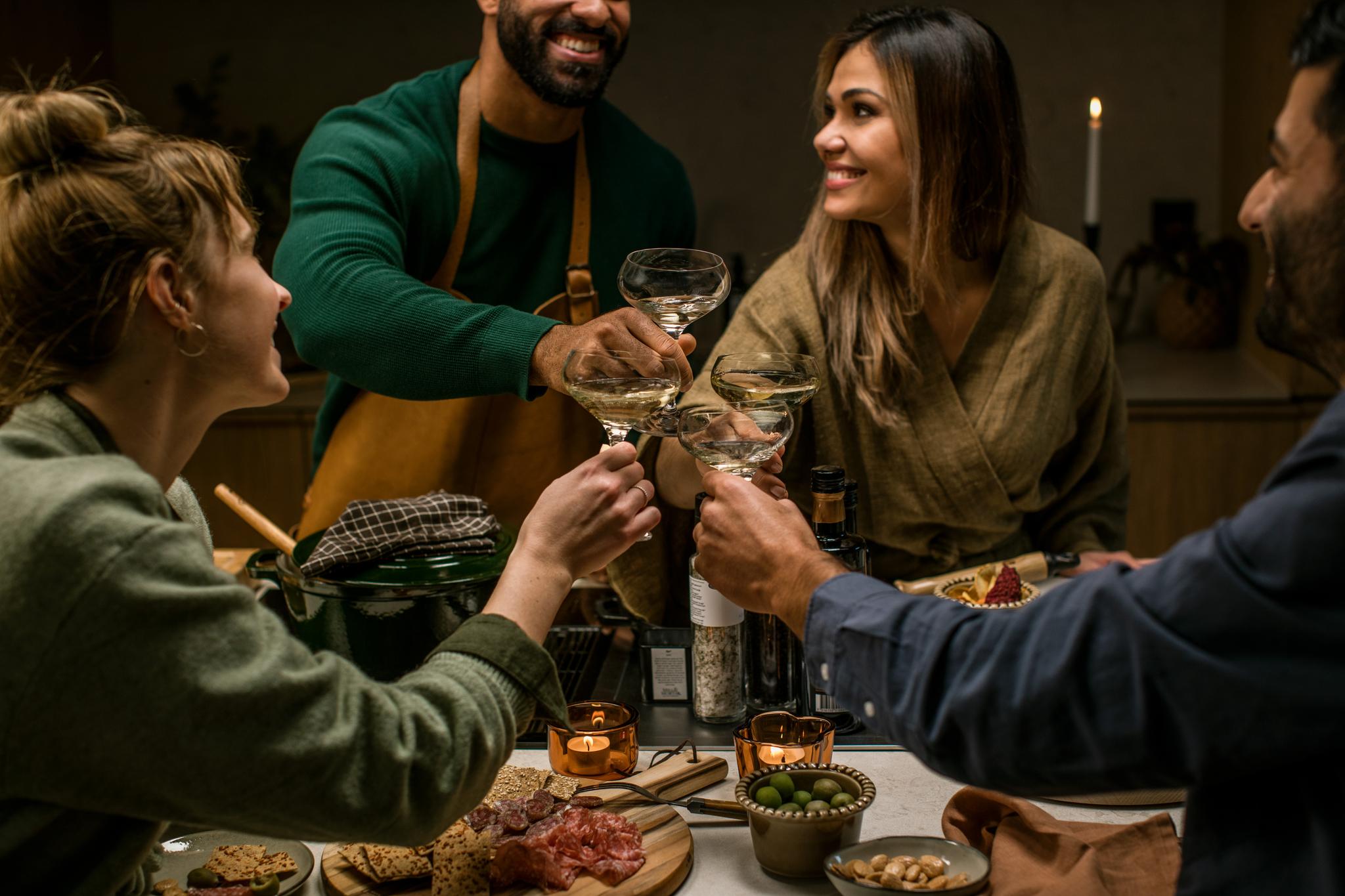 Vänner i ett kök som skålar i champagneglas