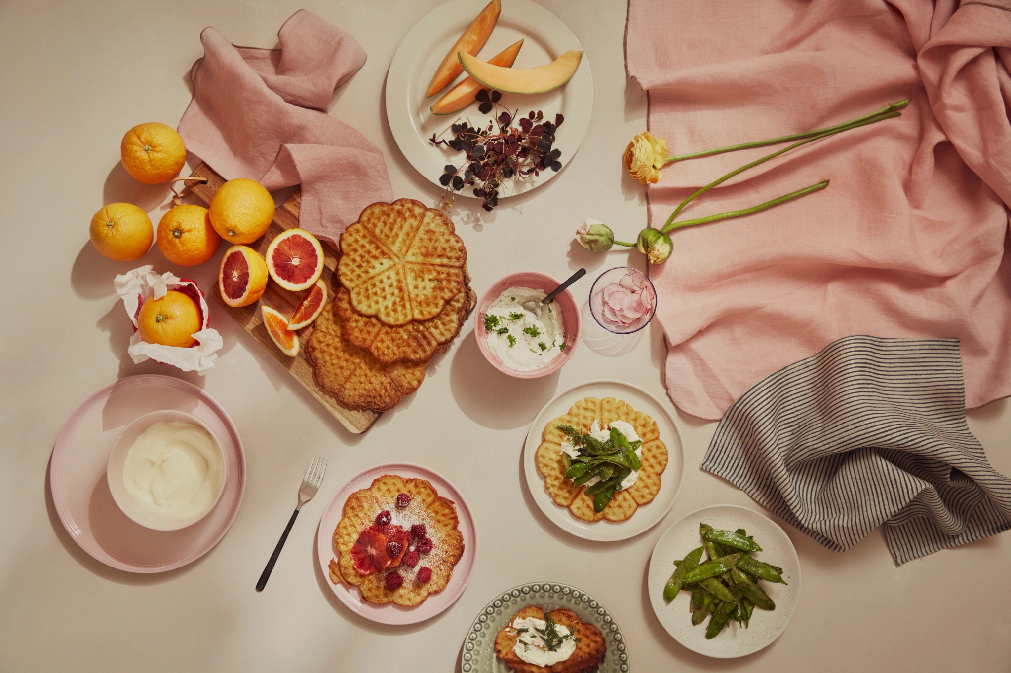 Våfflor med frukt, färska blodapelsiner och grädde arrangerade på ett bord.