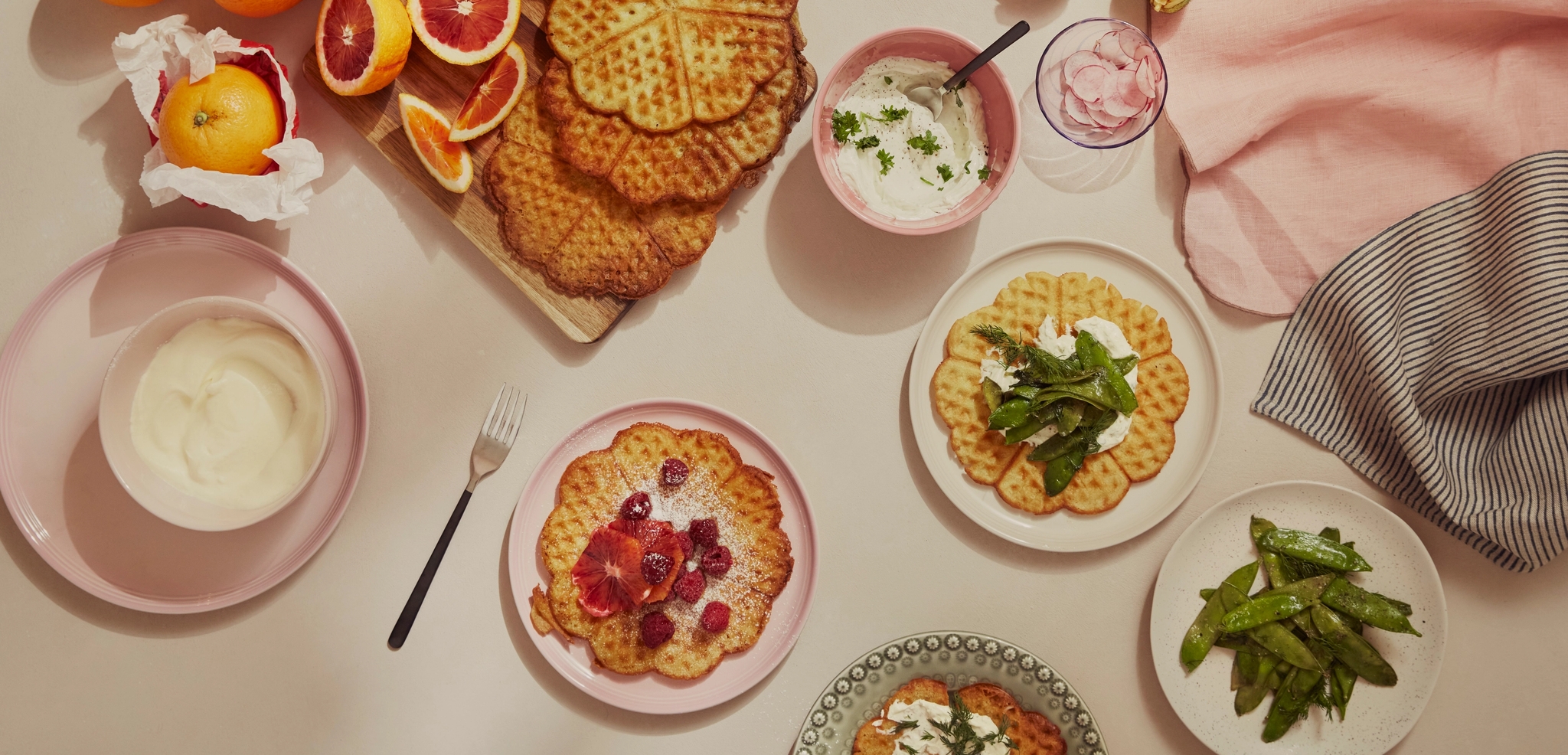 Våfflor med frukt, färska blodapelsiner och grädde arrangerade på ett bord.