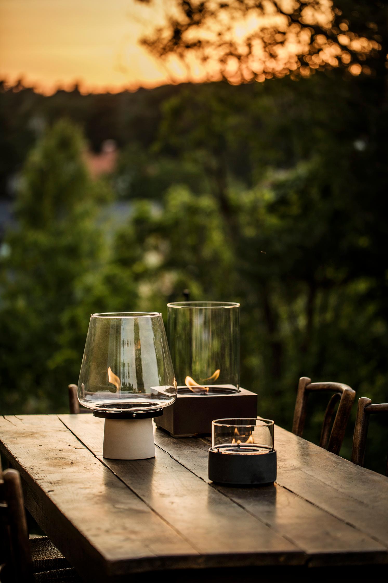 ett träbord med två ljus på och en solnedgång i bakgrunden