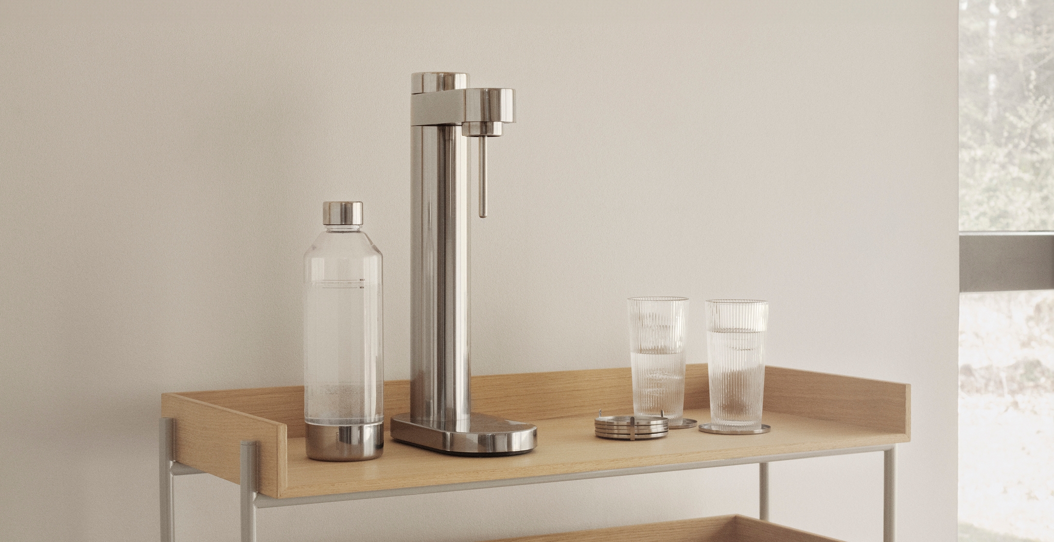 Minimalistisk kökshylla i ljust trä med kolsyremaskin, glas och karaff i modern skandinavisk inredning.