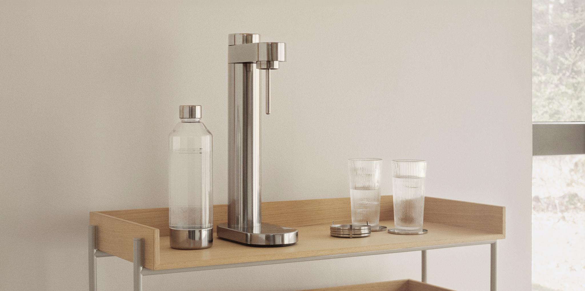 Minimalistisk kökshylla i ljust trä med kolsyremaskin, glas och karaff i modern skandinavisk inredning.