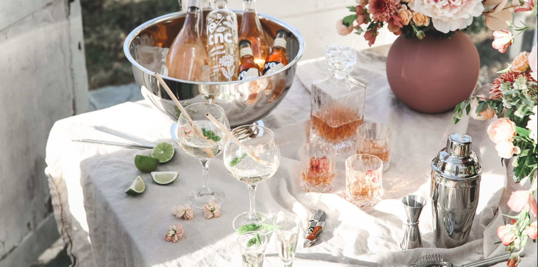 Pöytä cocktaileilla ja juomatarvikkeilla sekä kevätkukkia