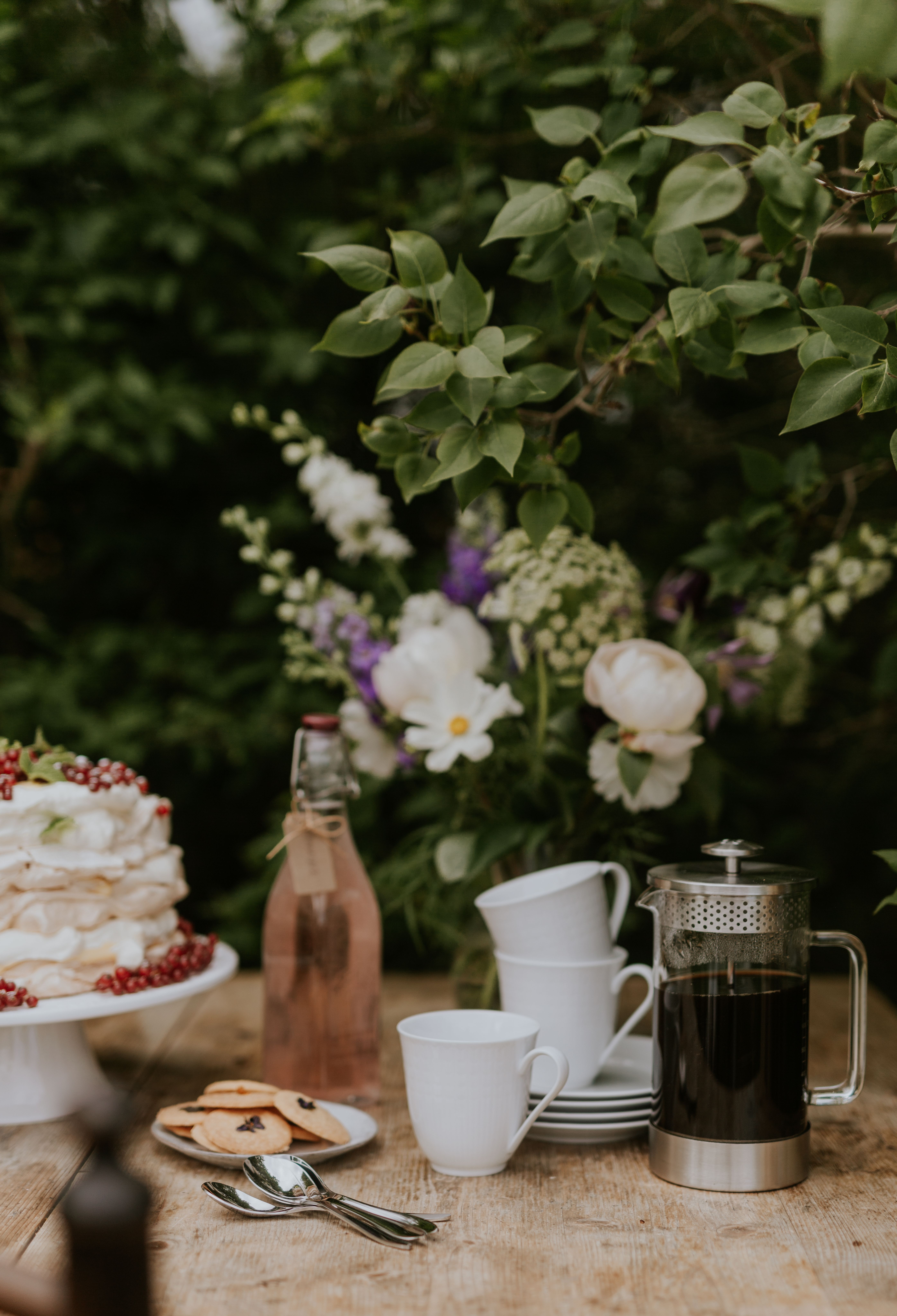 Kaffepress med kaffe och koppar på ett träbord utomhus