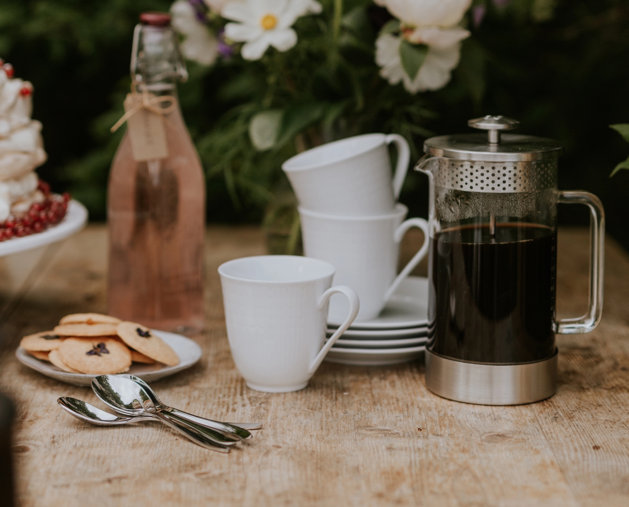 Kaffepress med kaffe och koppar på ett träbord utomhus