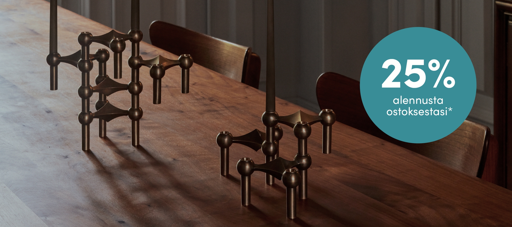 Kolme messinkistä modulaarista kynttilänjalkaa puisella pöydällä.