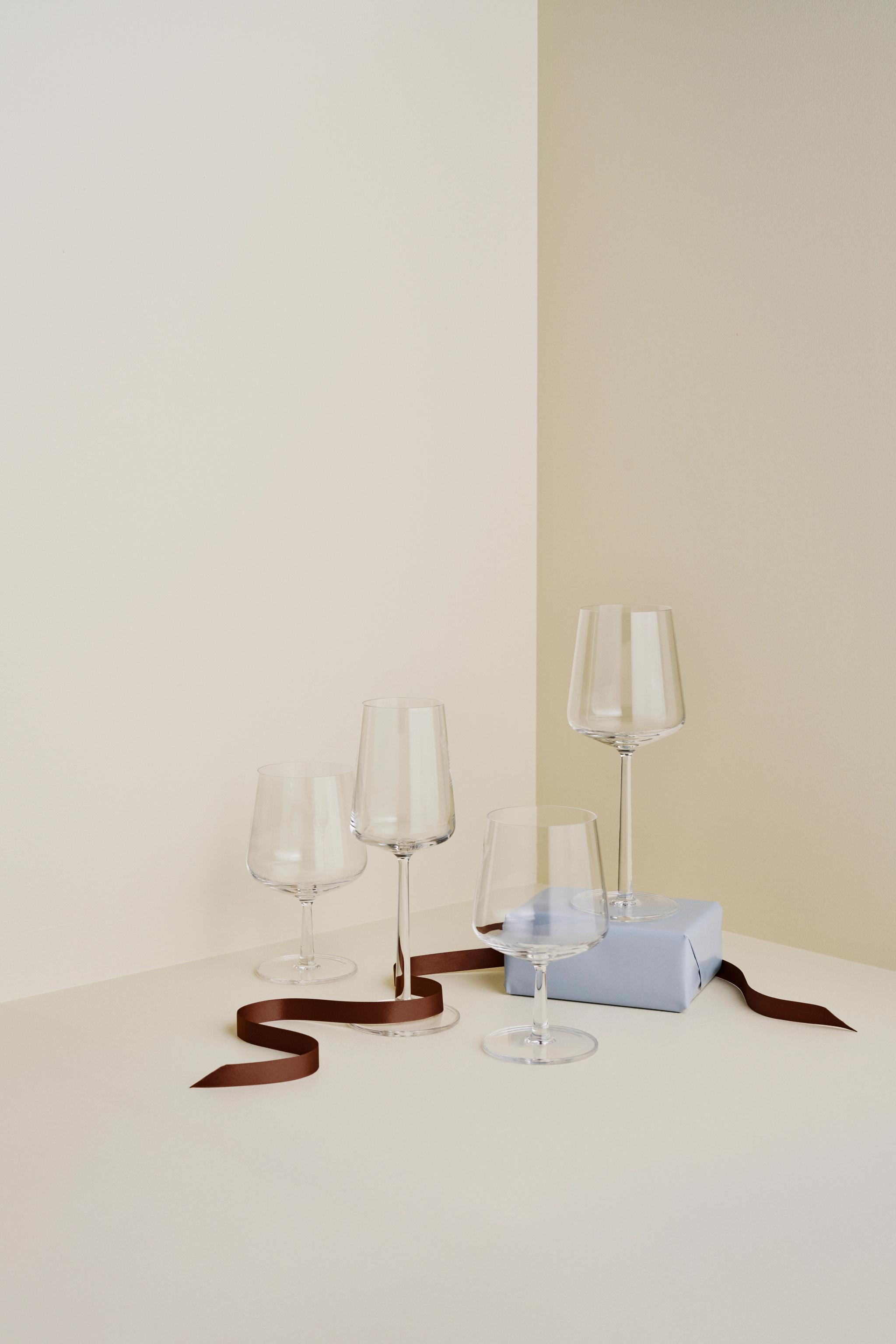 three wine glasses are sitting on a table next to a gift box .