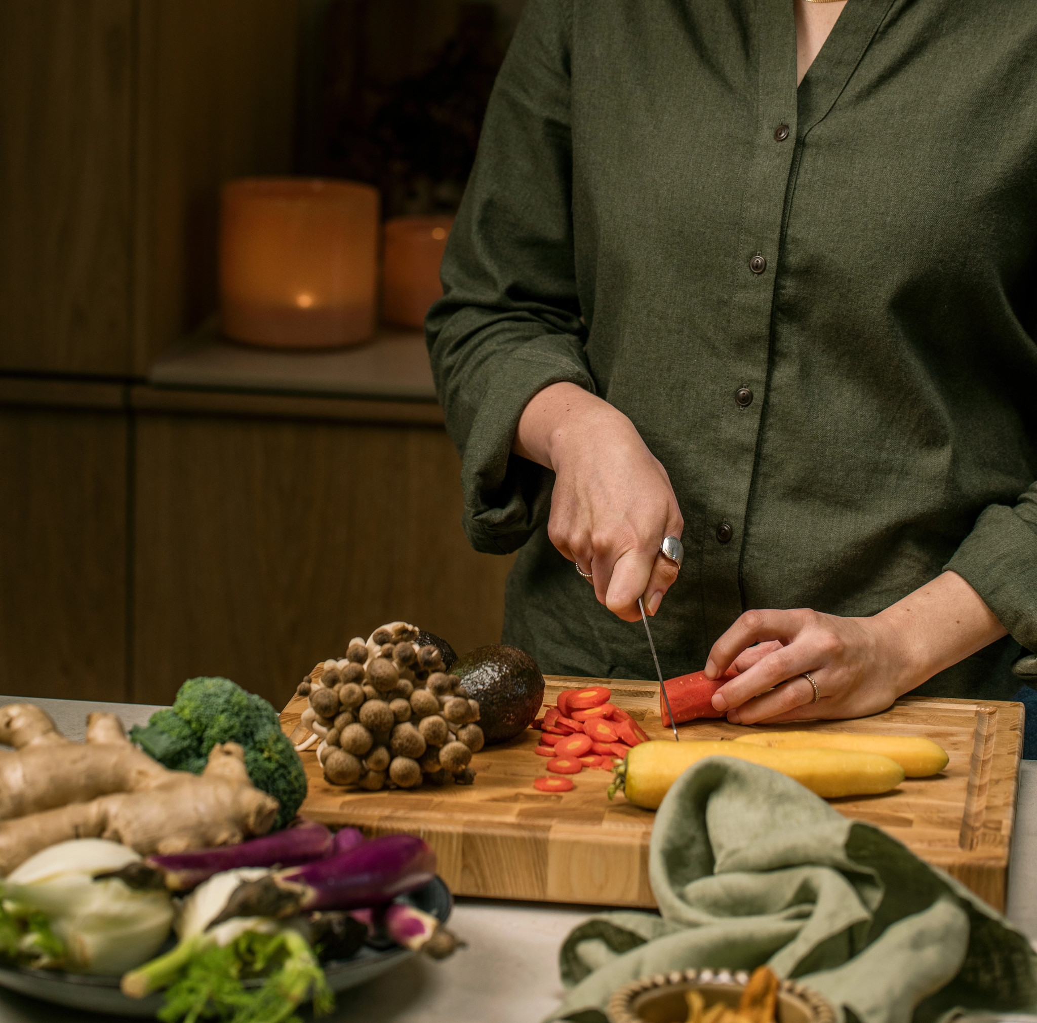 En kvinna står och skär grönsaker på en skärbräda av trä