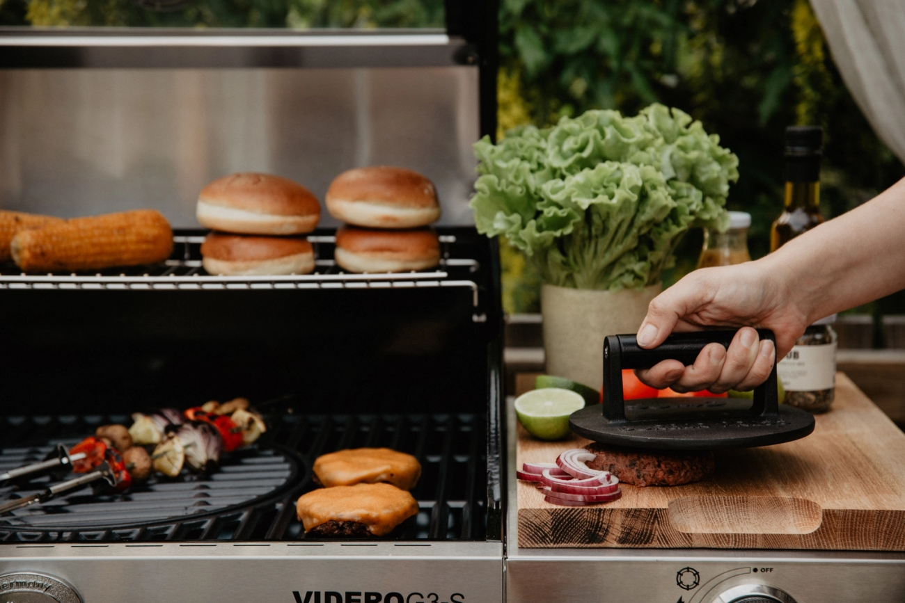 Hamburgerpress på stekbord vid grill