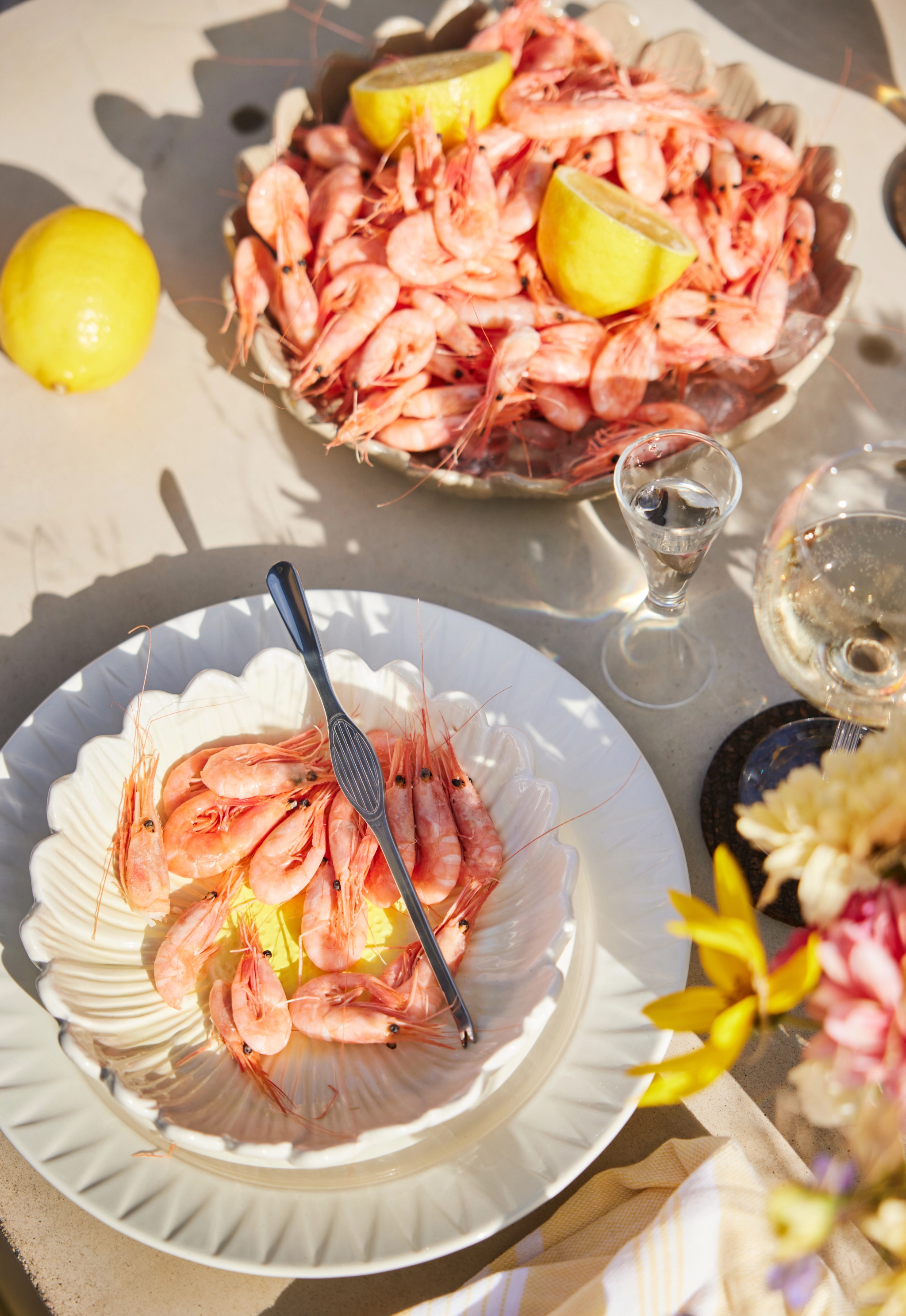 Äyriäisbuffet valkoinen kukanmuotoinen kulho täynnä katkarapuja sitruunan kera