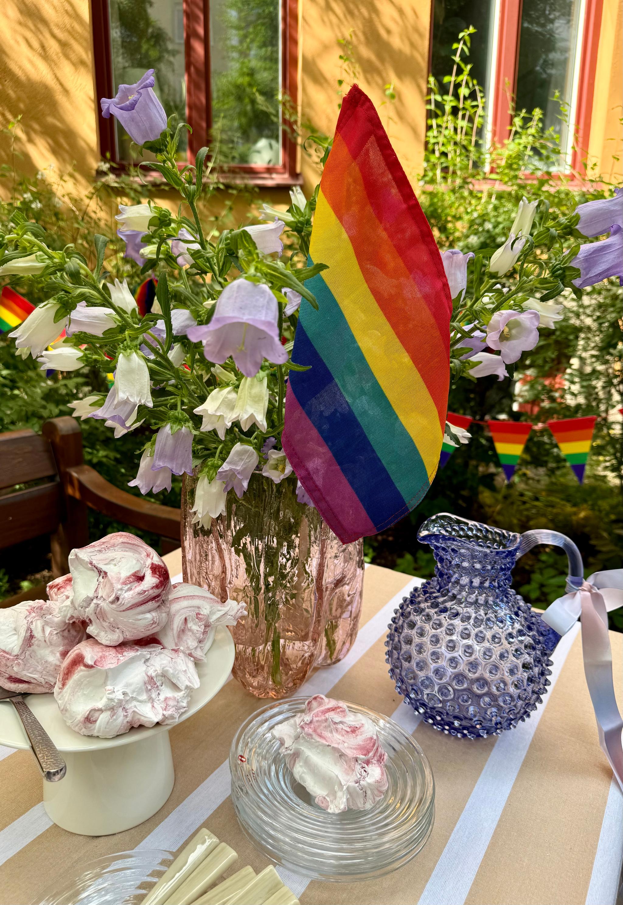 a table with a vase of flowers and a rainbow flag