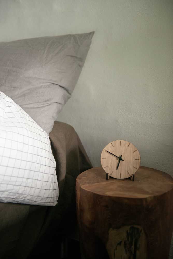 sovrum med fokus på ett trä nattduksbord och en trä klocka med svarta detaljer