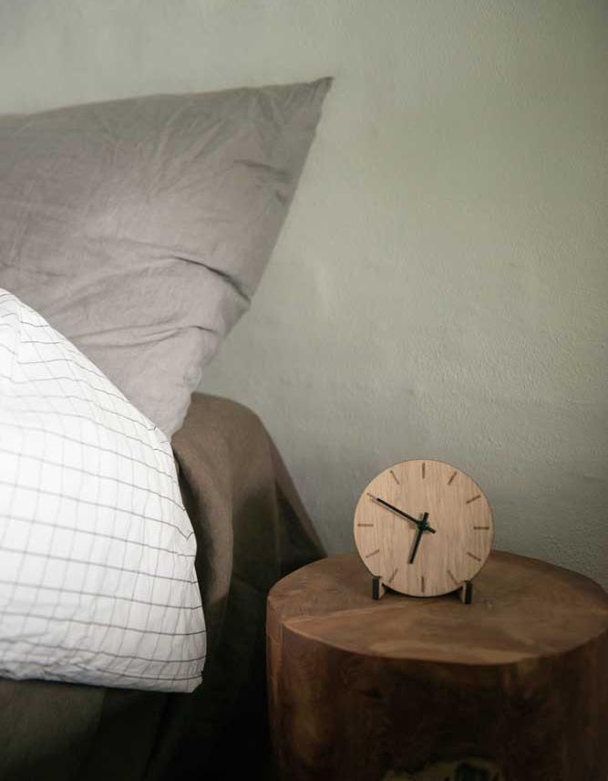 sovrum med fokus på ett trä nattduksbord och en trä klocka med svarta detaljer