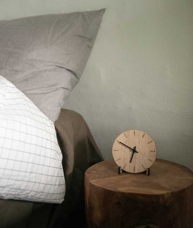 sovrum med fokus på ett trä nattduksbord och en trä klocka med svarta detaljer