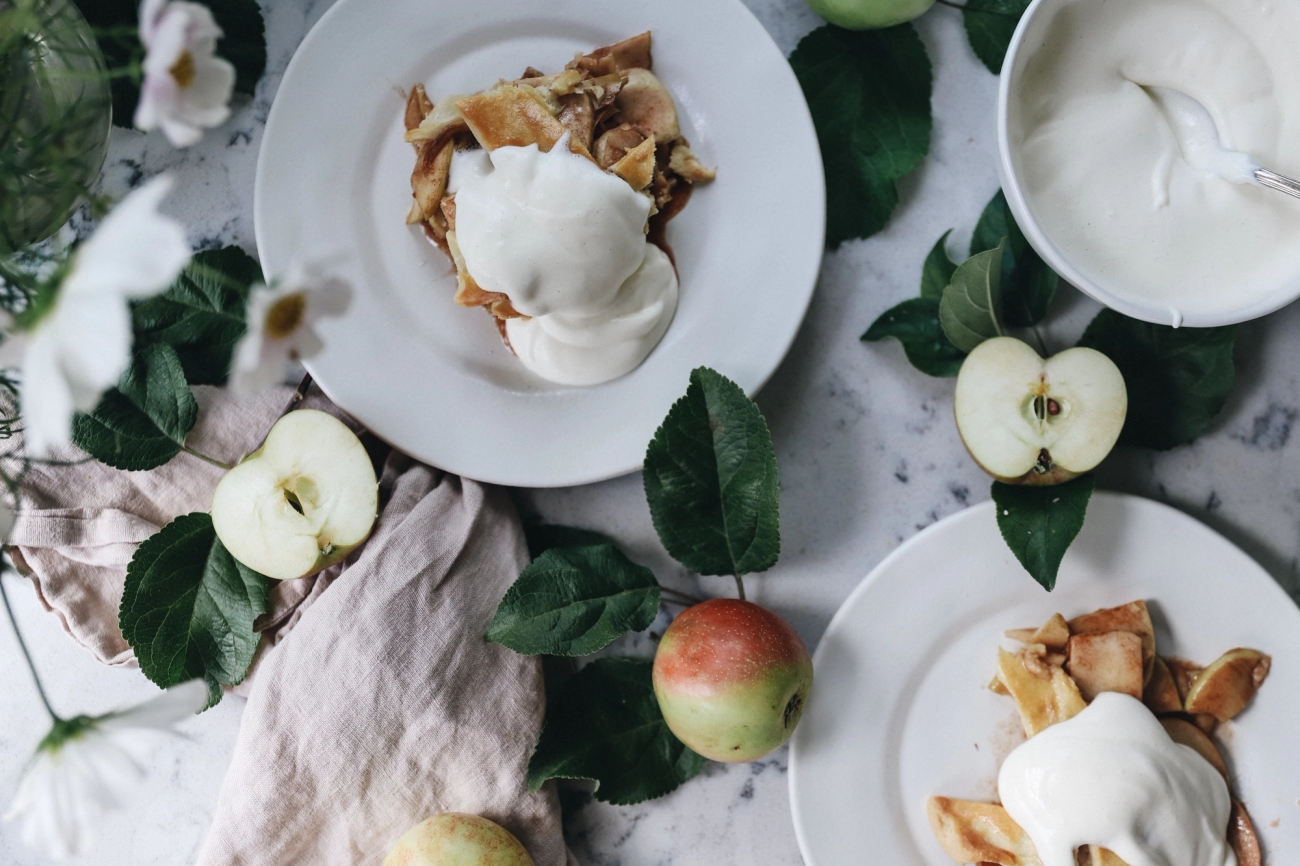 Vita tallrikar med äppelpaj och vispad grädde