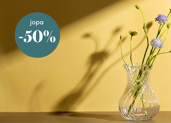 Keltainen mainoskuva, jossa lasimaljakossa on kukkia ja vihreässä ympyrässä teksti ”jopa -50 %” alennuksesta.
