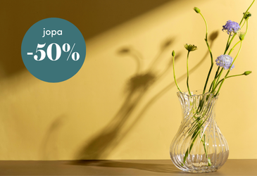 Keltainen mainoskuva, jossa on lasimaljakossa kukkia ja vihreässä ympyrässä teksti ”jopa -50 %” alennuksesta.