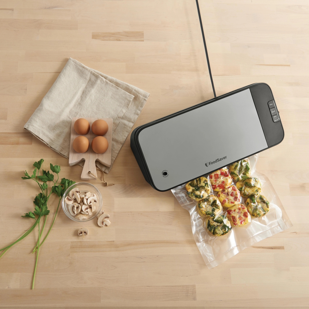 FoodSaver vakuumikone sulkemassa minipiirakoita sisältävää pussia puisella keittiötasolla.