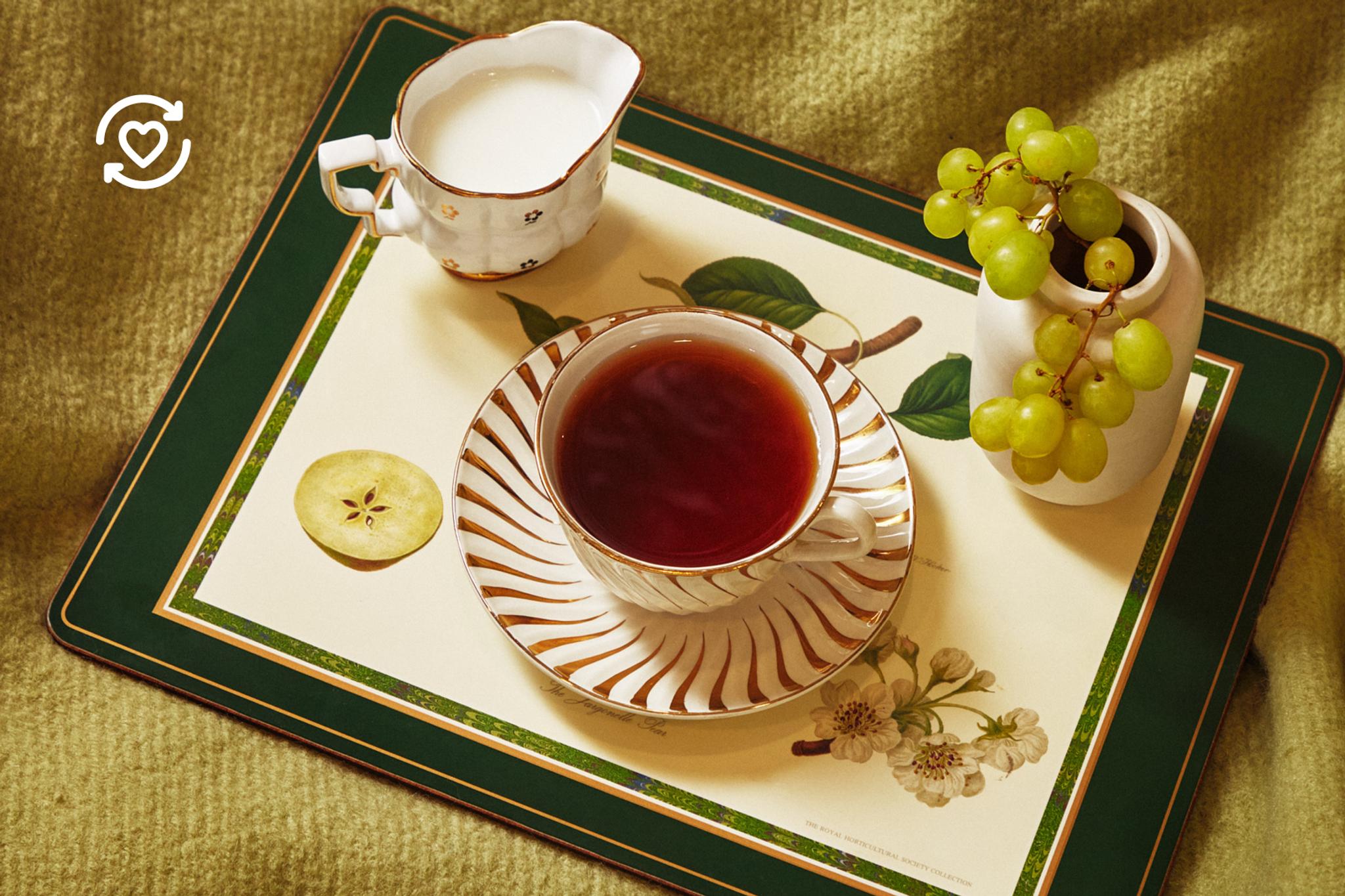 En tekopp och en liten mjölkkanna på en blommig bricka