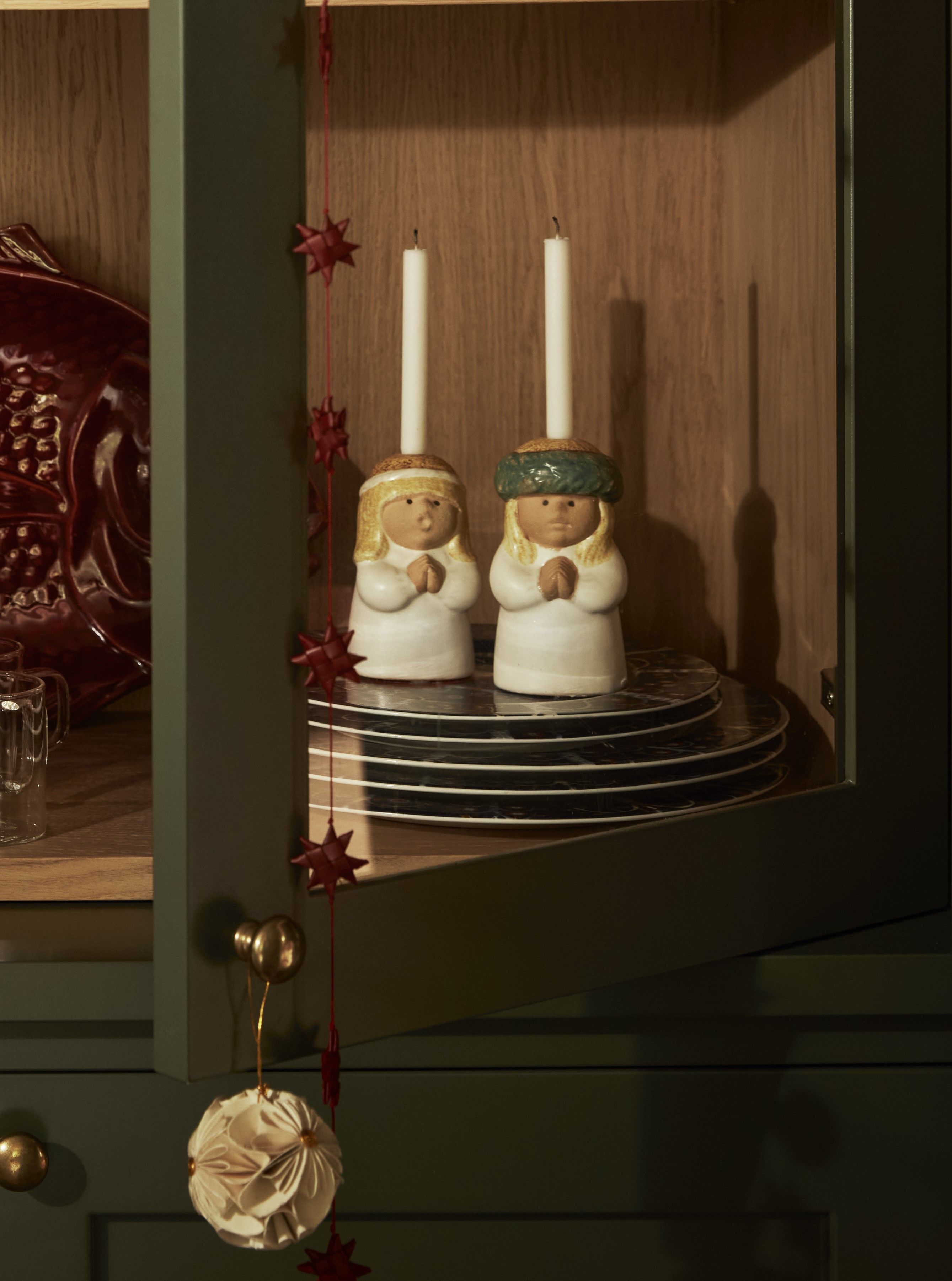 Lysestaker i form av barn som går i luciatog står i et skap