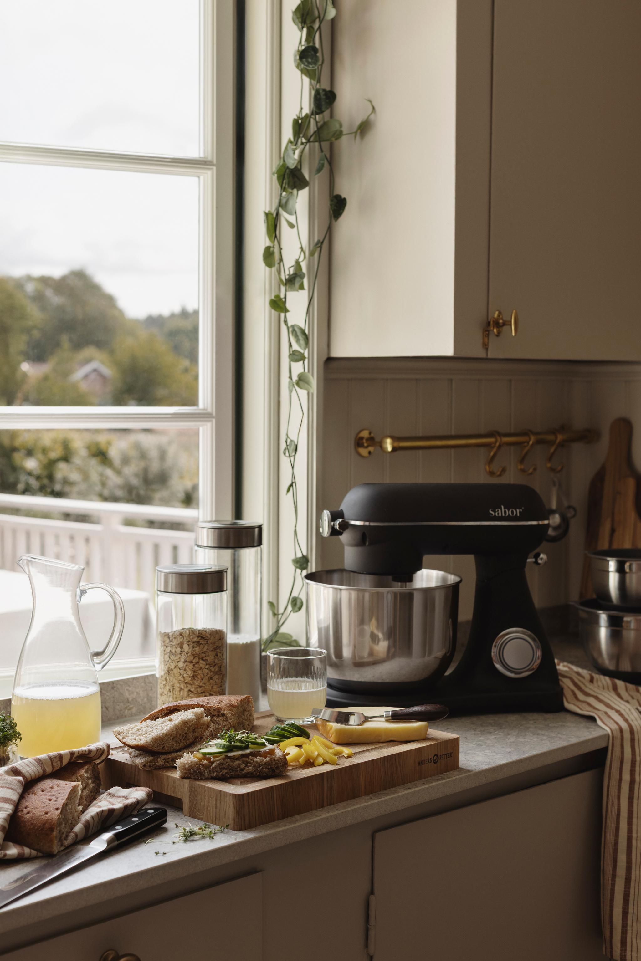 En svart kjøkkenmaskin står på en kjøkkenbenk ved siden av et vindu