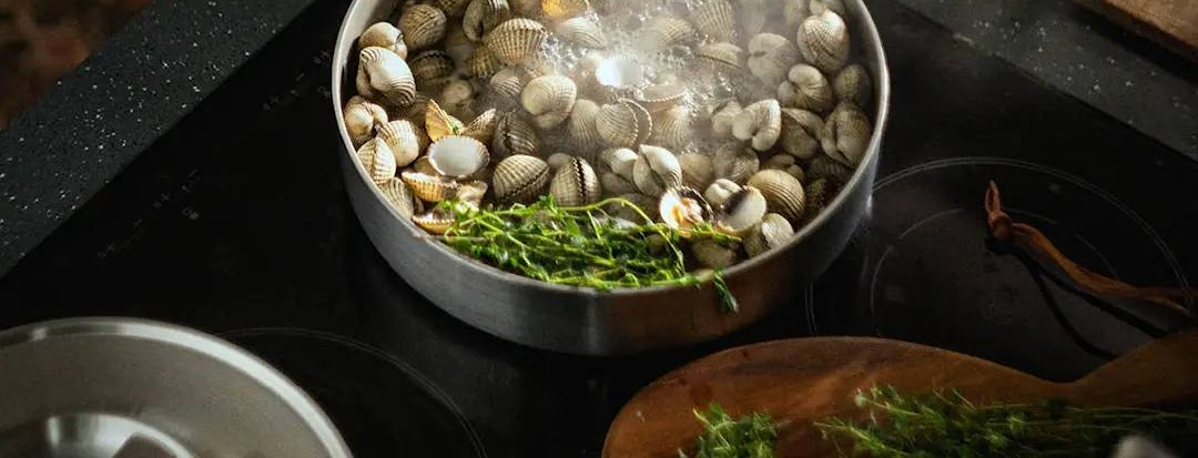 fiskars Norden Steel Paistokasari täynnä simpukoita induktioliedellä