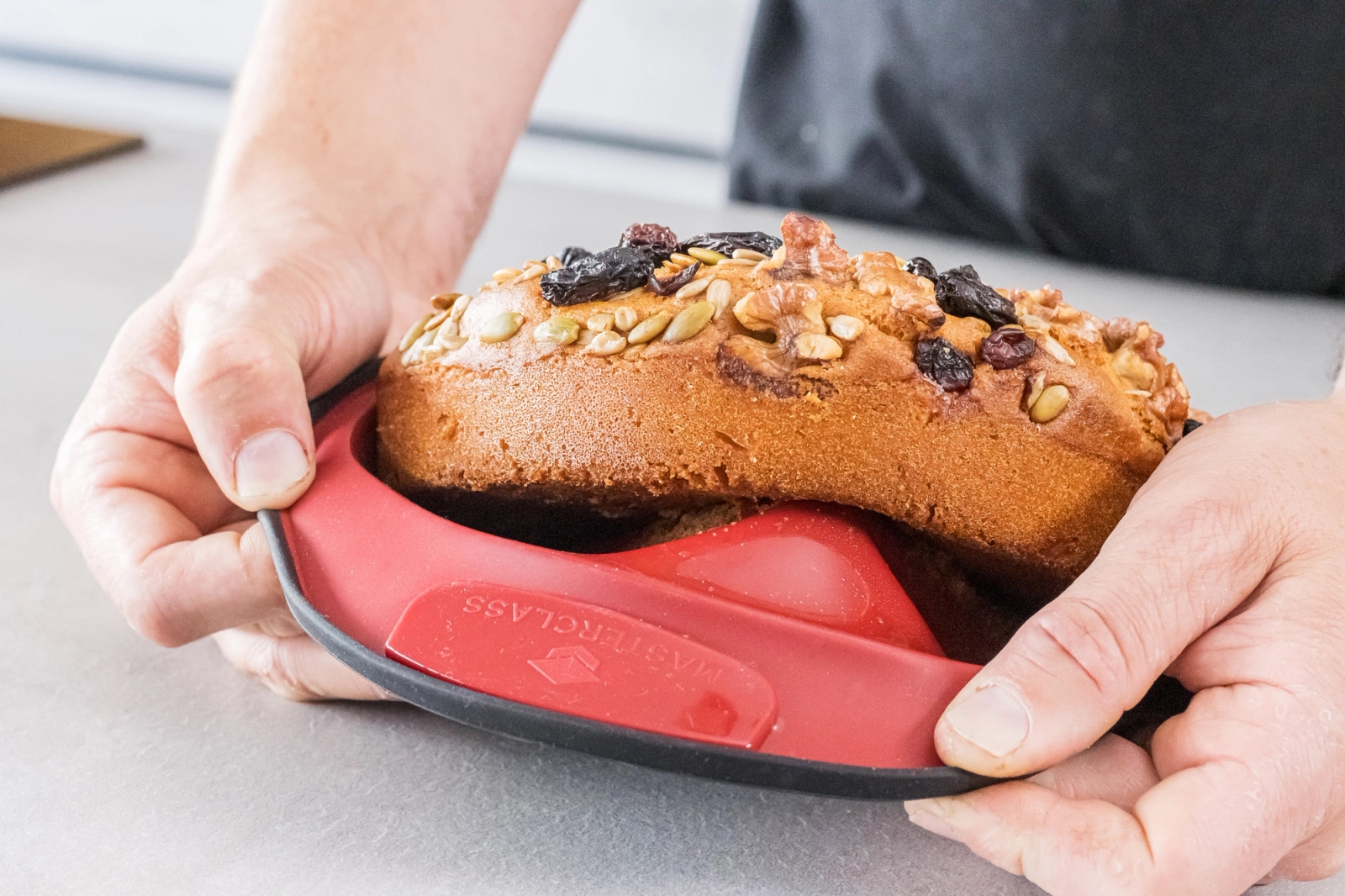 Person lossar ett bröd ur en röd silikonform på en köksbänk