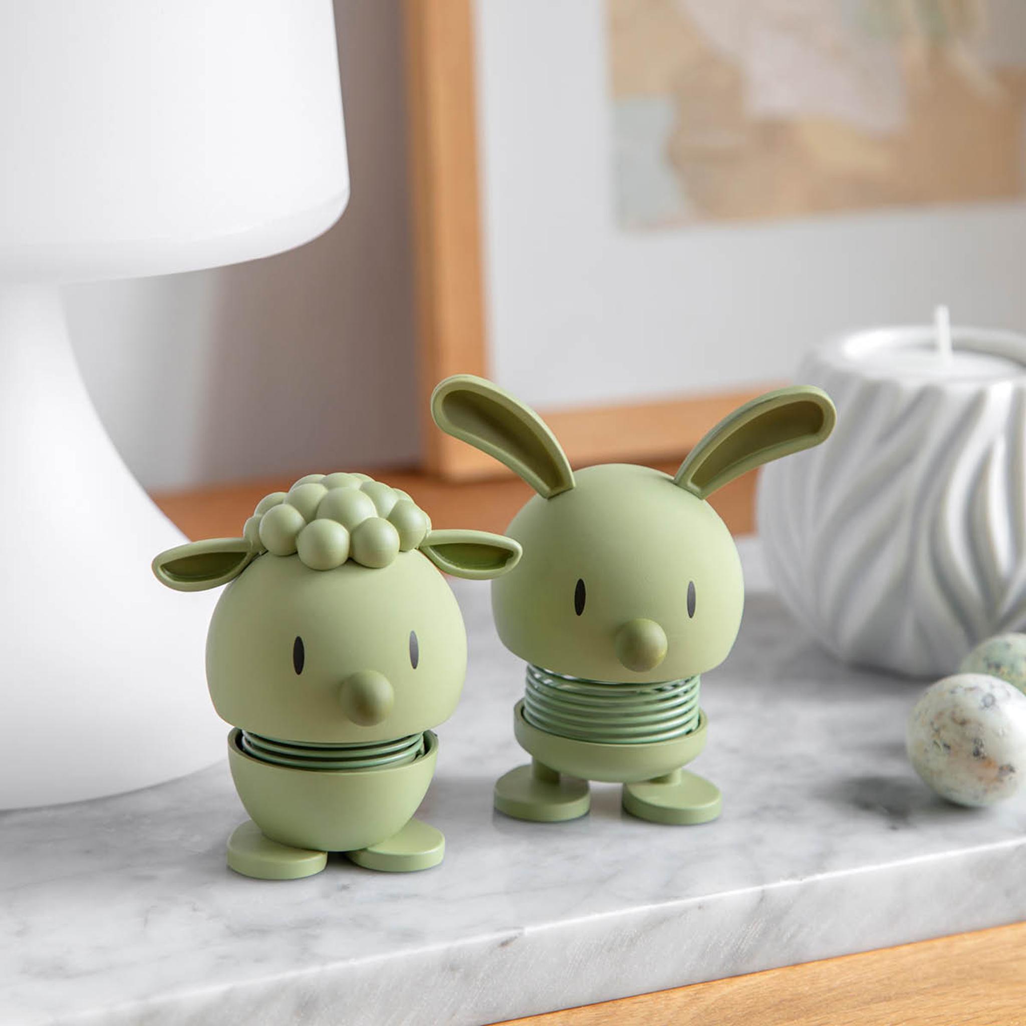 To lysegrønne fjærbelastede figurer, en sau og en kanin, på en marmorovertflate